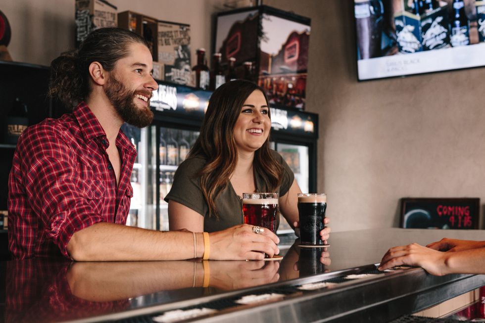 A couple sitting at a bar with a glass of beer