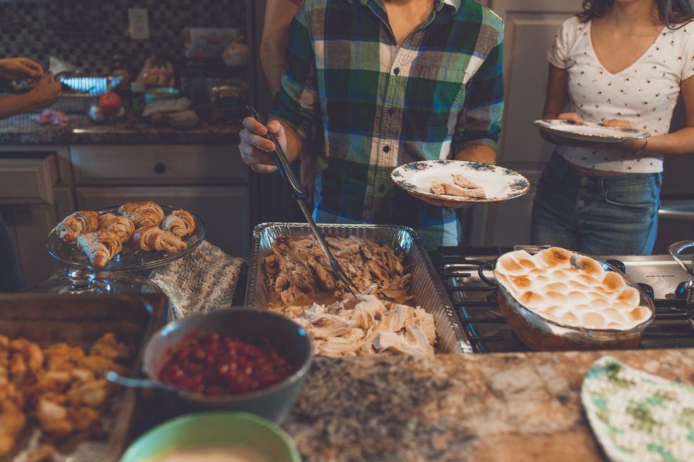 Buffet-style spread with person in plaid shirt taking food