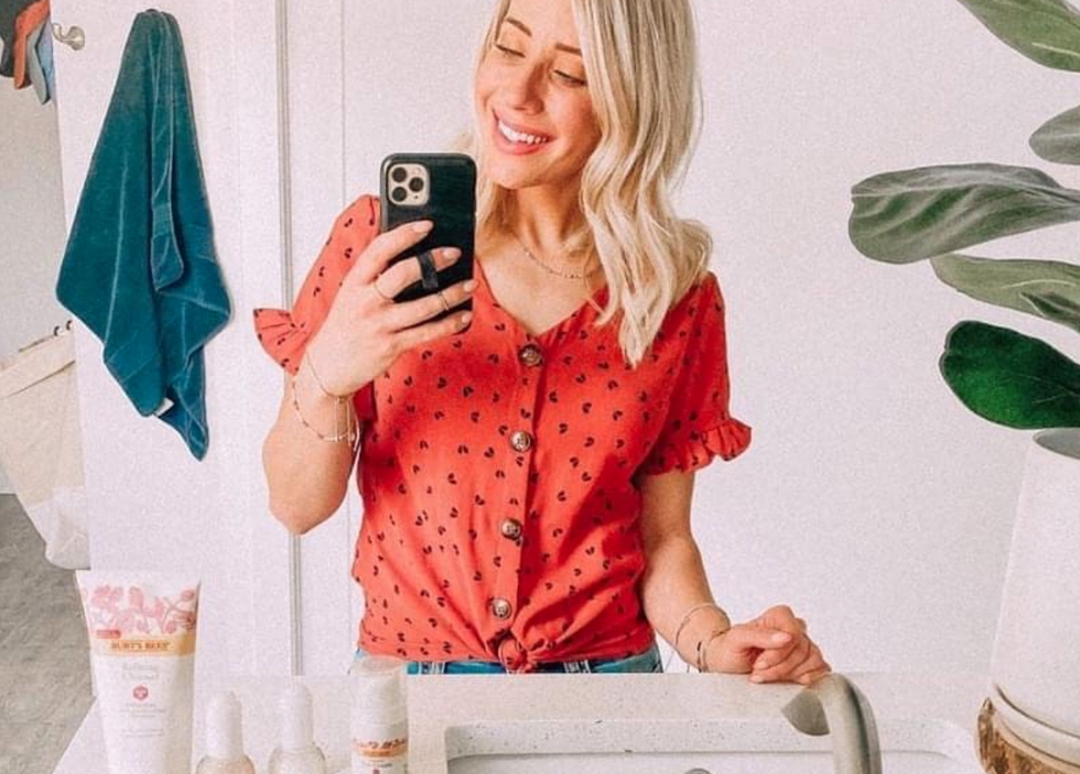 Girl taking bathroom selfie with Burt's Bees products on counter