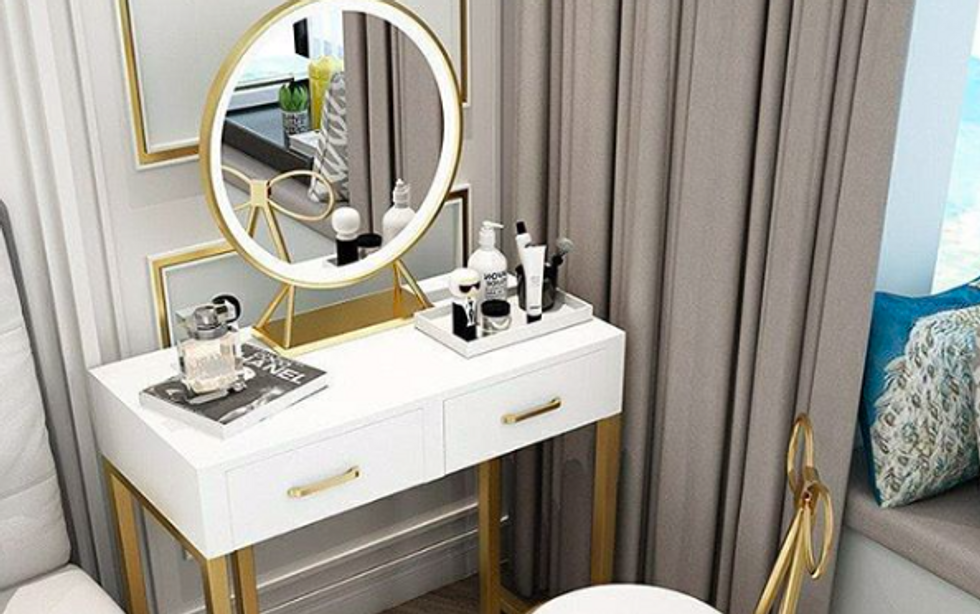 white desk with gold accents and gold/LED-light rimmed circular mirror on top of it