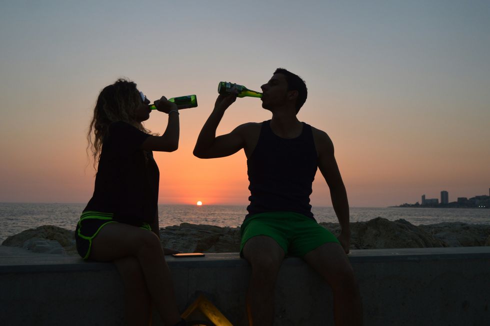 woman and man drink beers at the beach