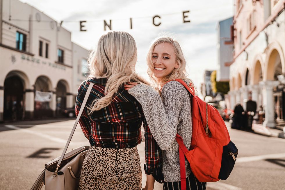 woman in black and white long sleeve shirt carrying girl in red jacket in Venice beach